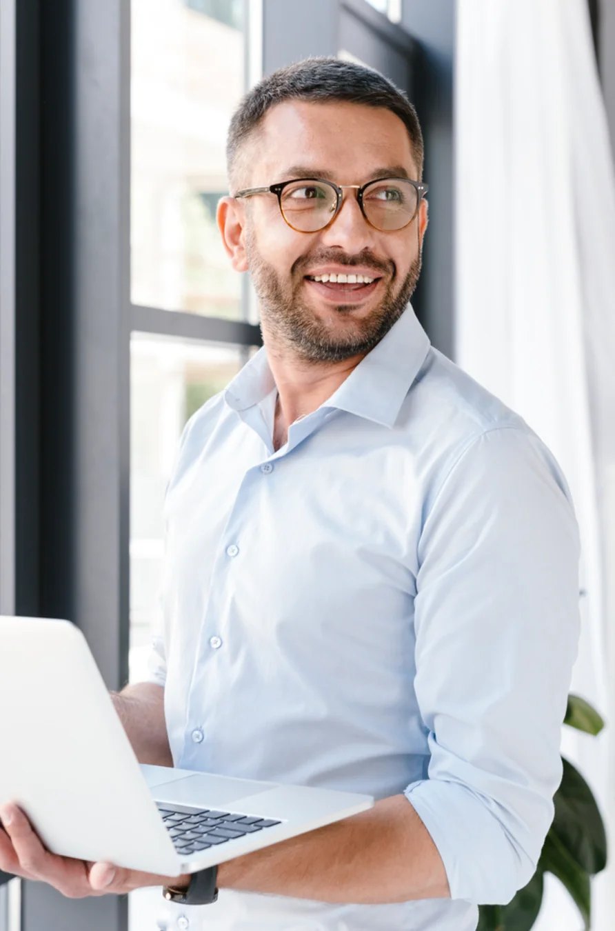 Un homme portant des lunettes et tenant un ordinateur portable